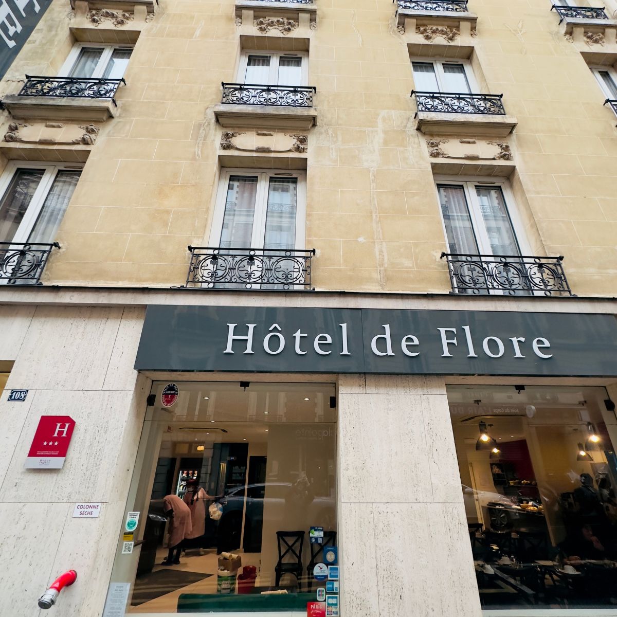 The front of a hotel in France. The sign says "Hotel de Flore"