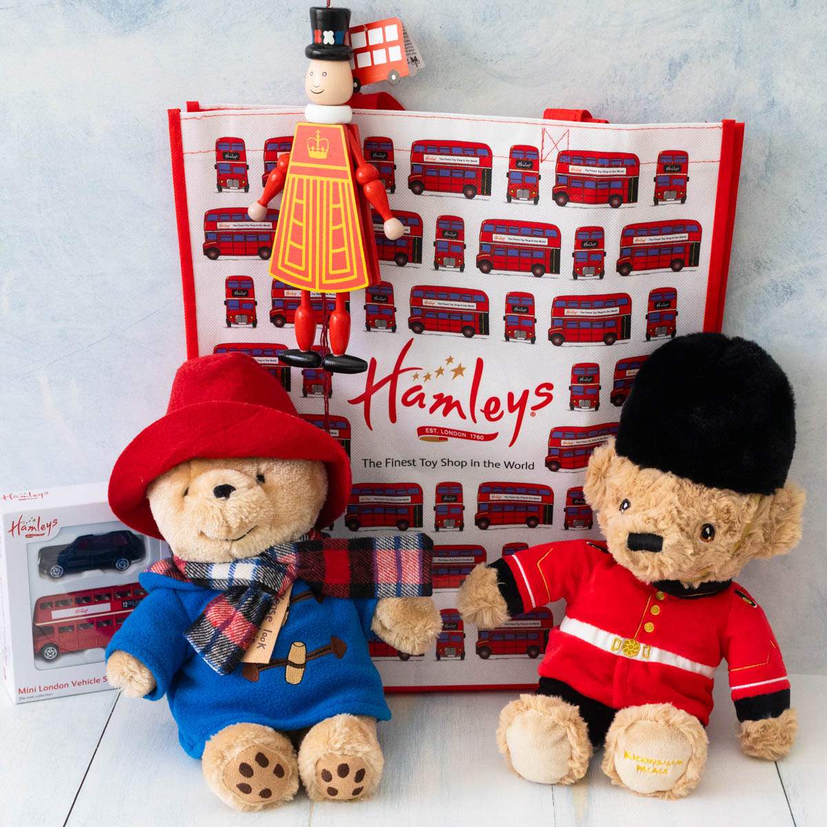 Two stuffed bears, a set of toy cars, a London shopping bag, and a pull toy.