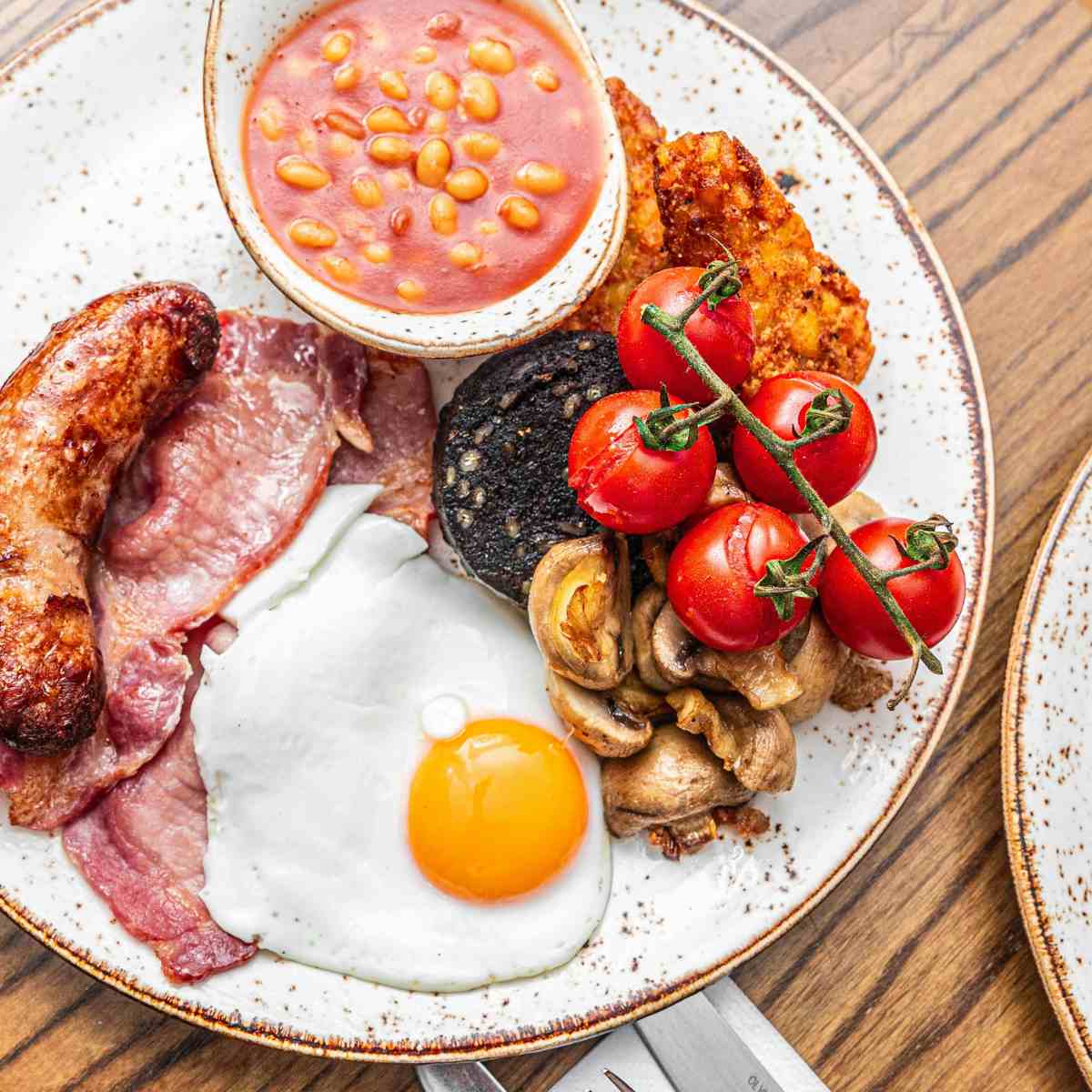 A plate of traditional Irish breakfast has black pudding under the tomatoes.