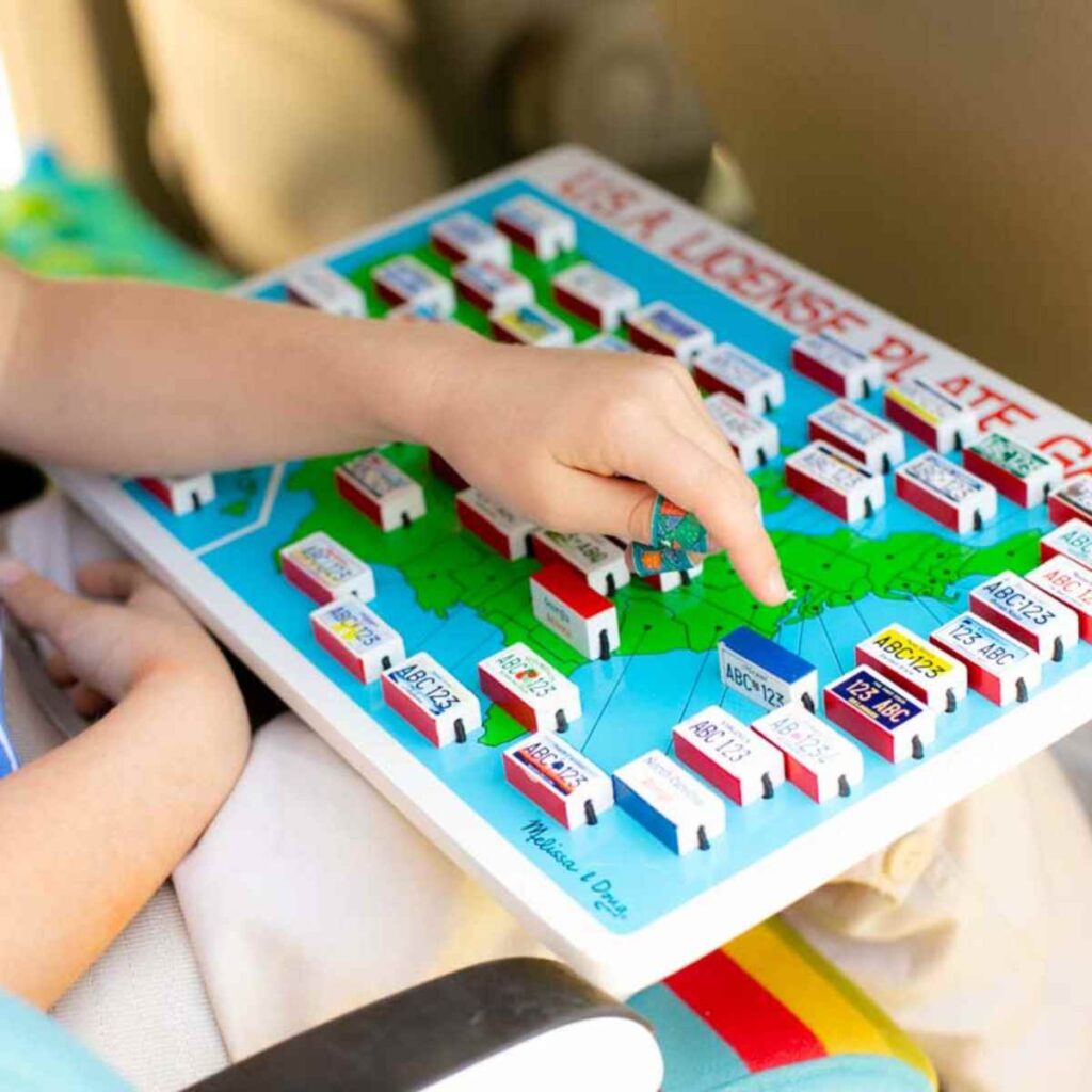 A young girl plays a wooden license plate game.