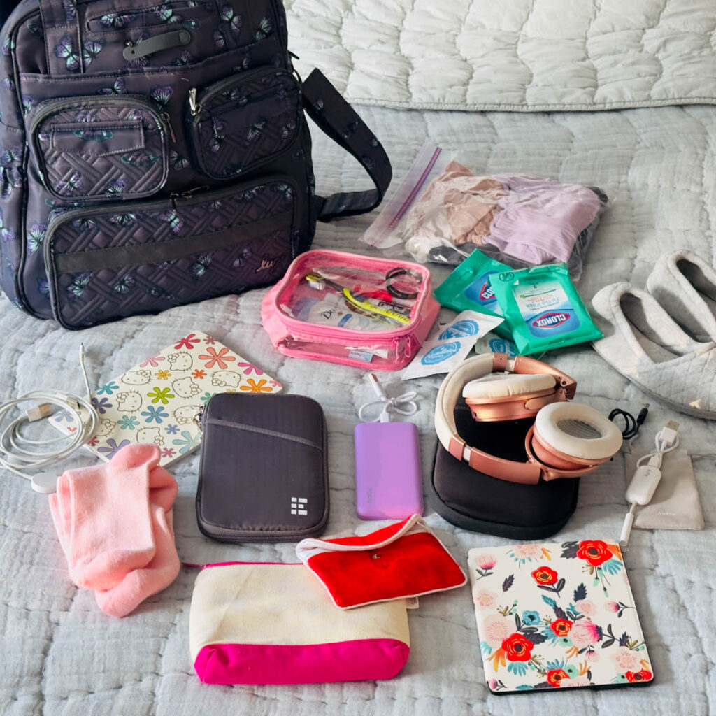 A carry on bag sits on the bed in front of all the items that go inside.