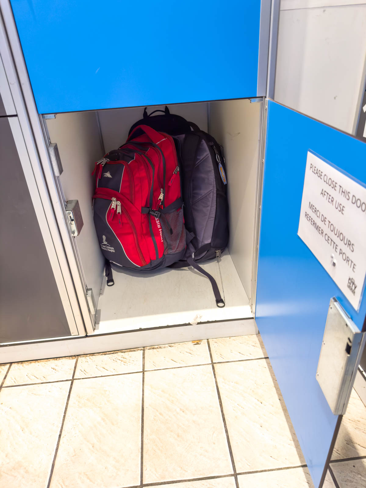 A backpack inside a locker with the door open.