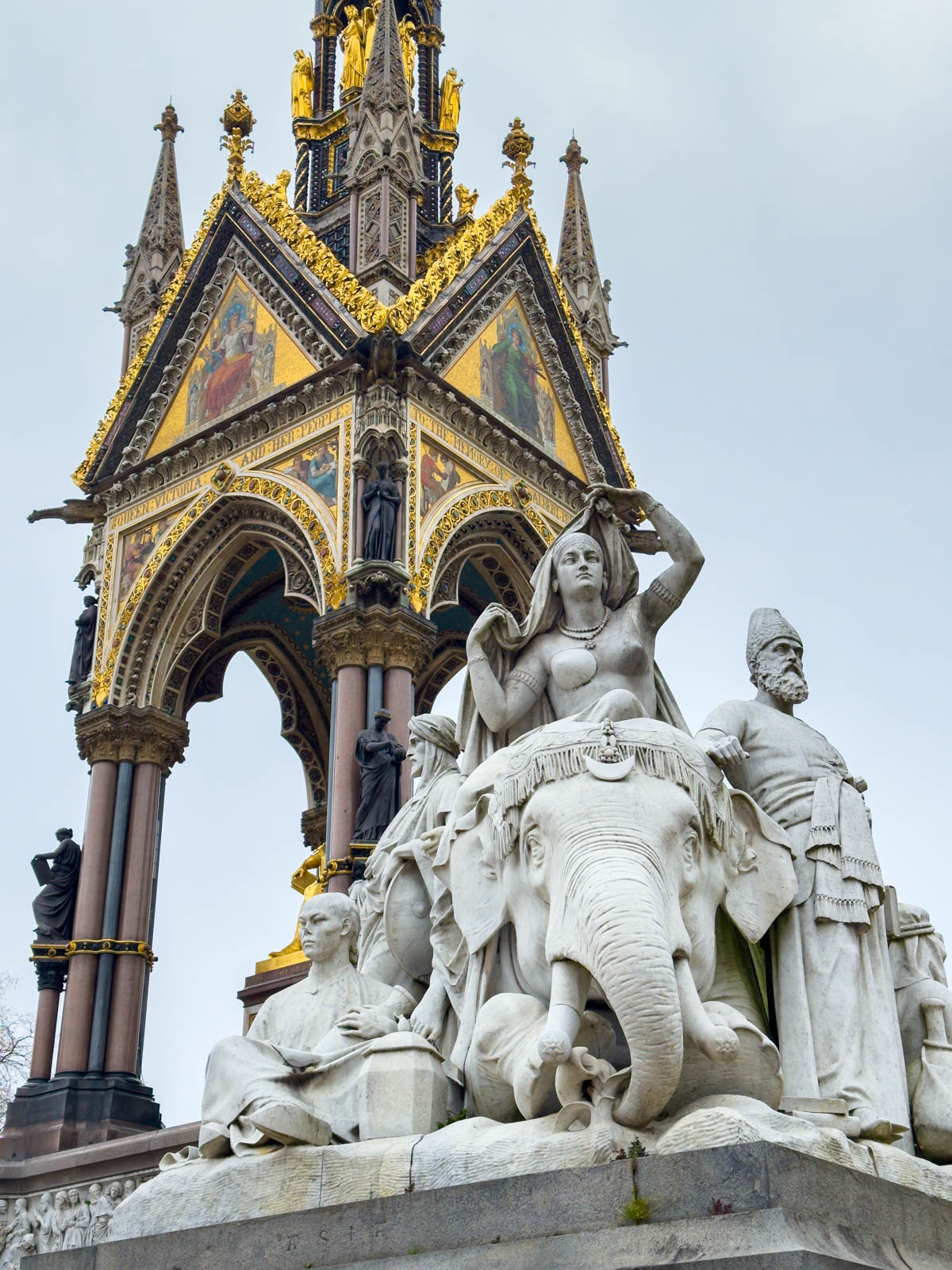 The top of the Prince Albert Memorial is gilded. A statue feating several figures is in the foreground.