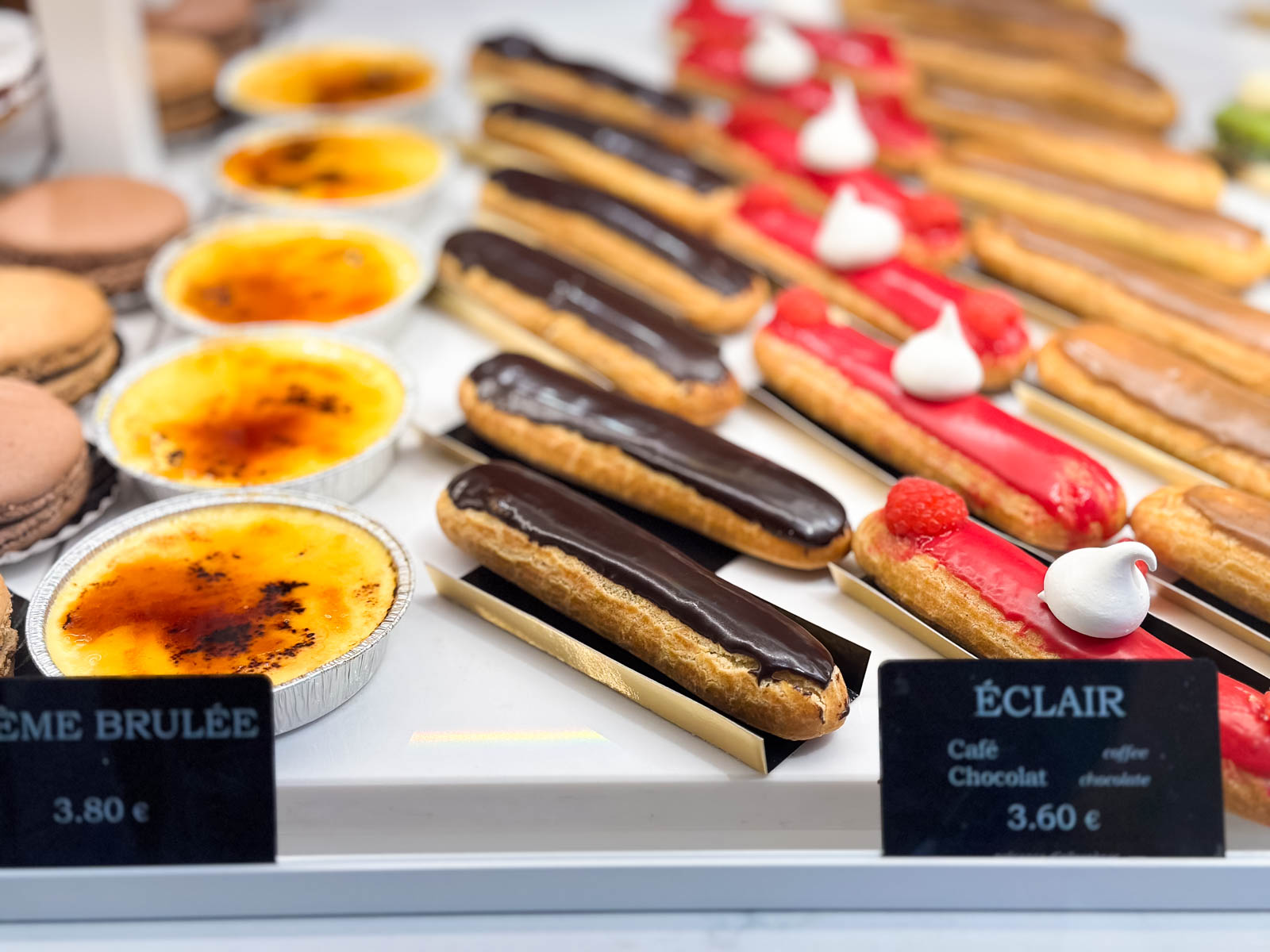 A bakery case has creme brulee and eclairs