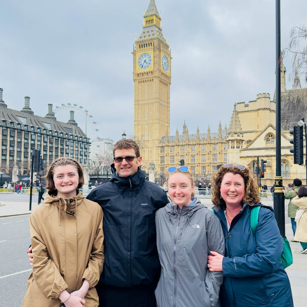 A family of four stands in front of Big Ben in London, England.