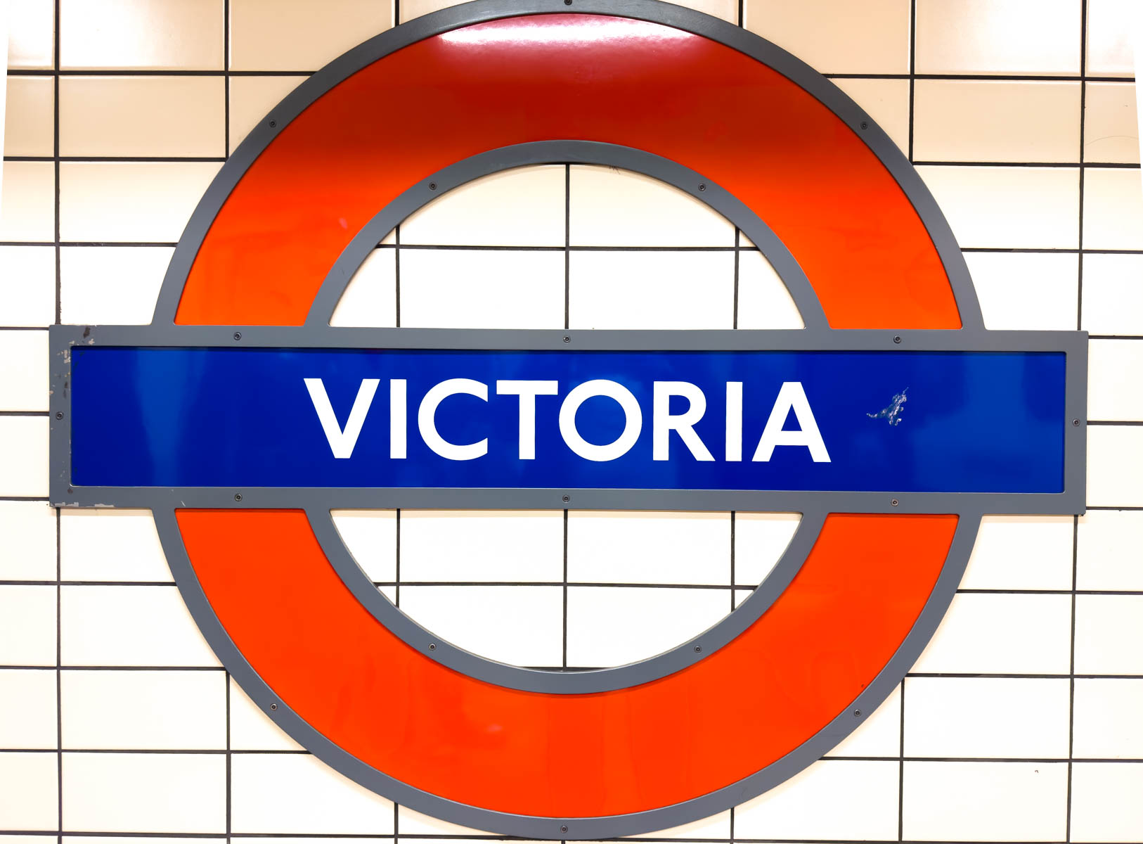 The red and blue circle of the Victoria Station sign in the London Underground.