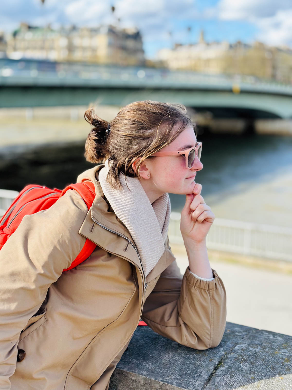 A young girl poses in front of the river in Paris.