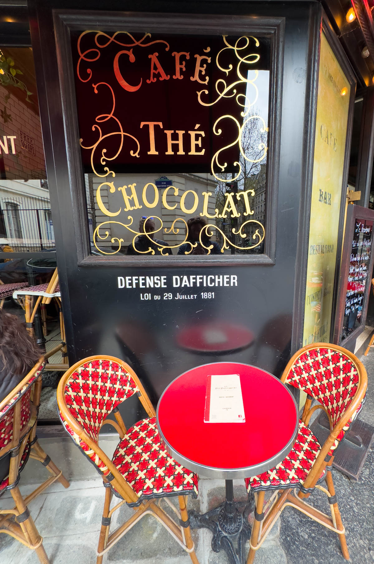 Two red cafe chairs and a small table in front of a cafe in Paris.