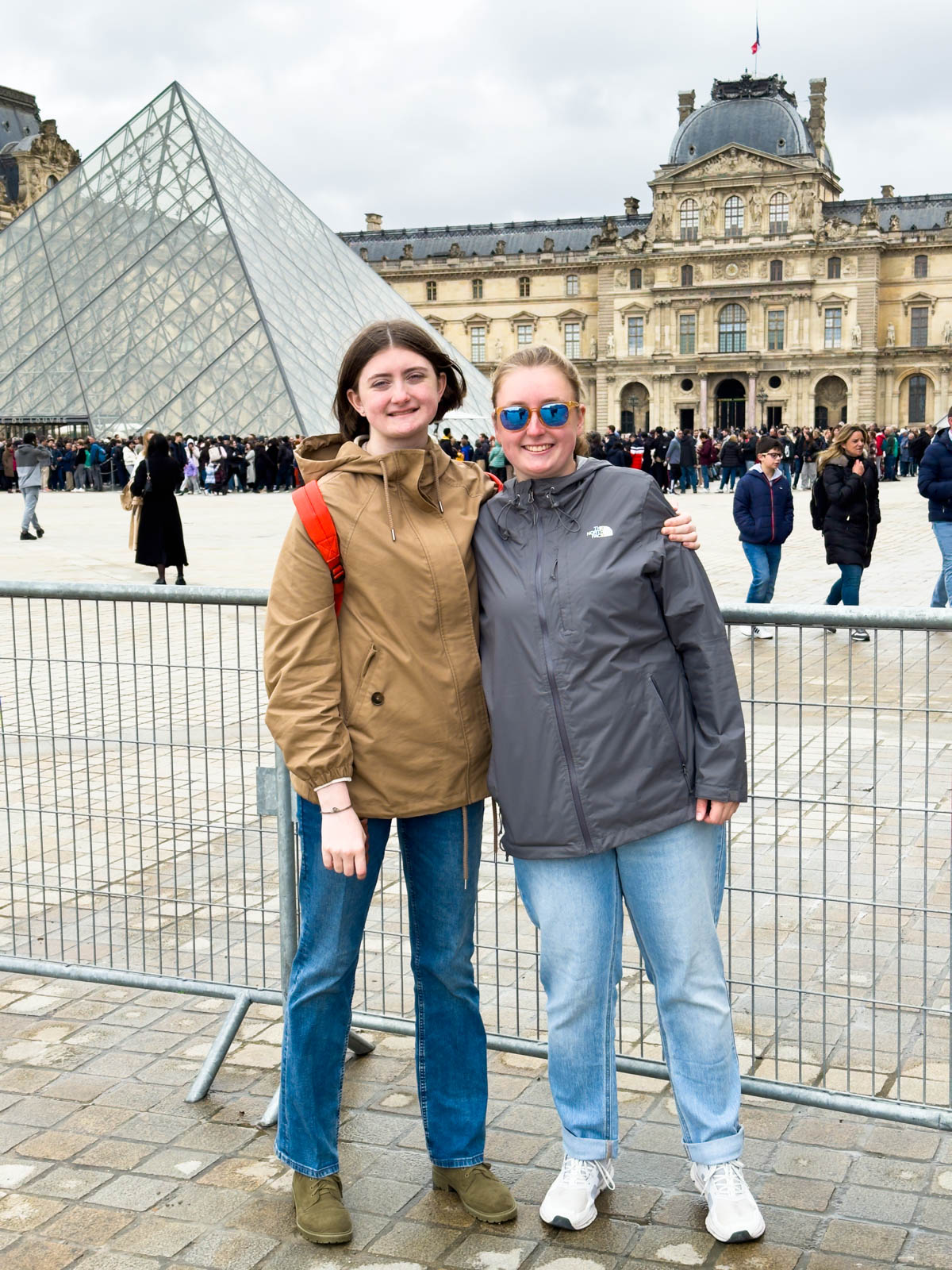 Two girls stand in front of the Louvre.