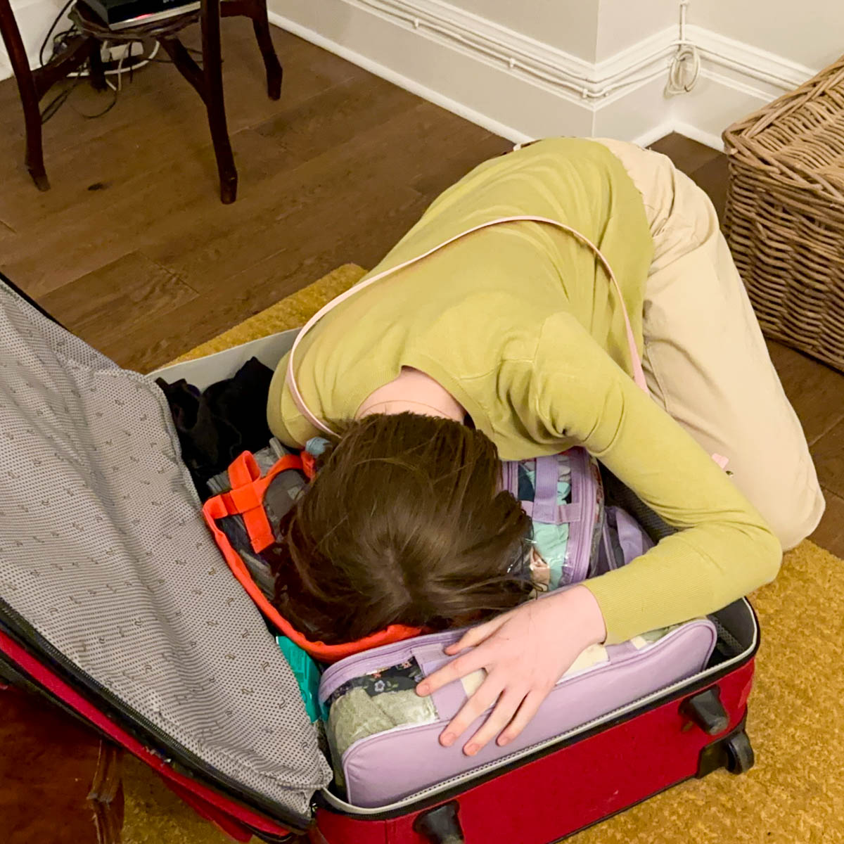 A girl hugs her clothes in her suitcase.