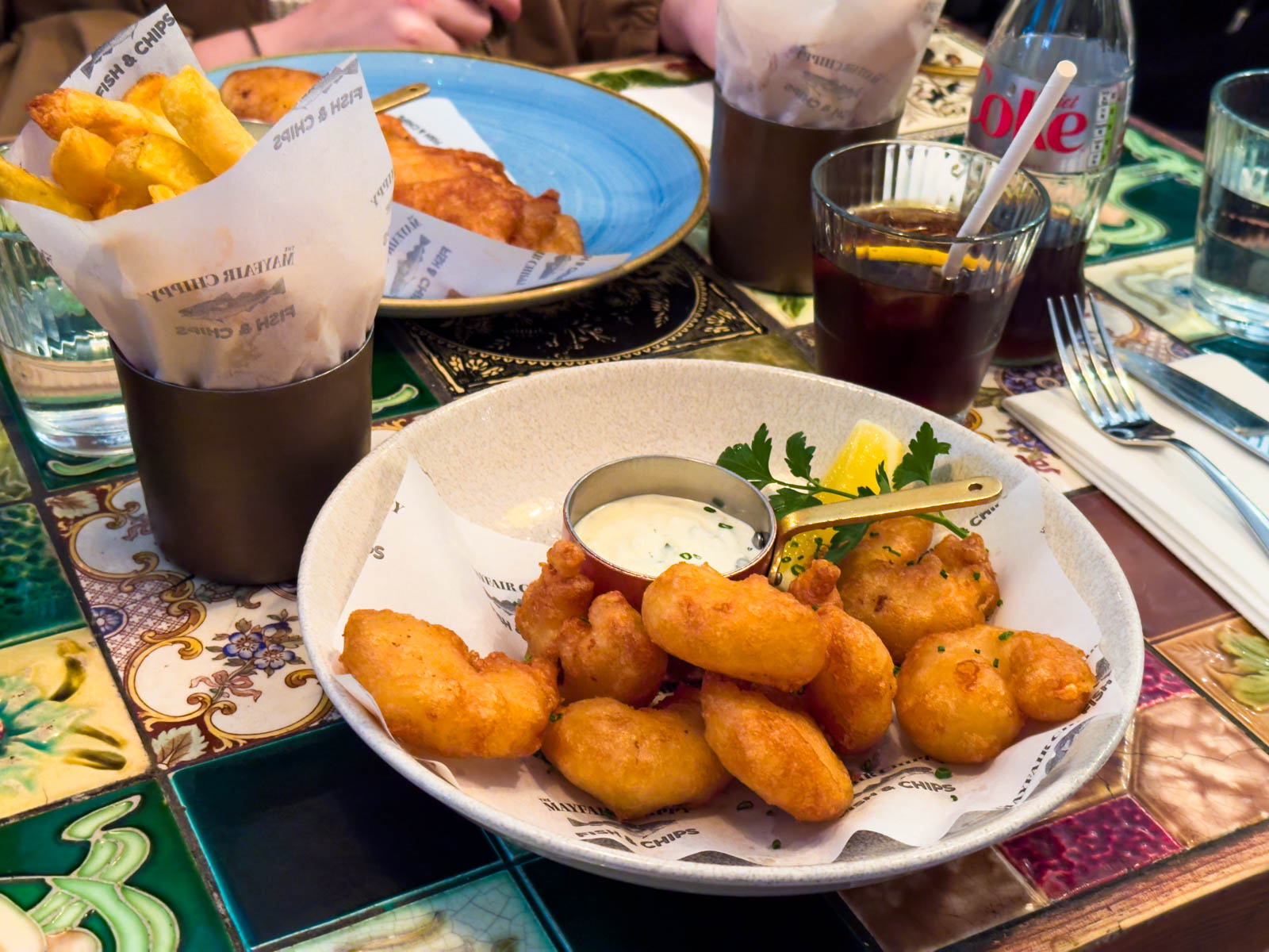 A plate of fried and battered prawns with tartar sauce.