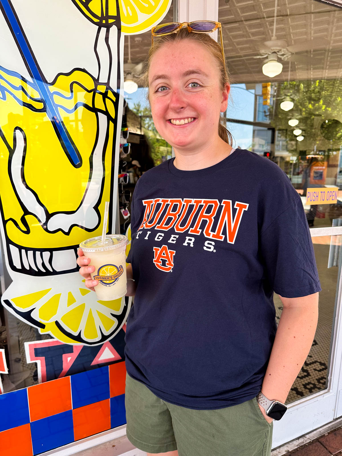 A girl in an Auburn t-shirt drinks a lemonade.