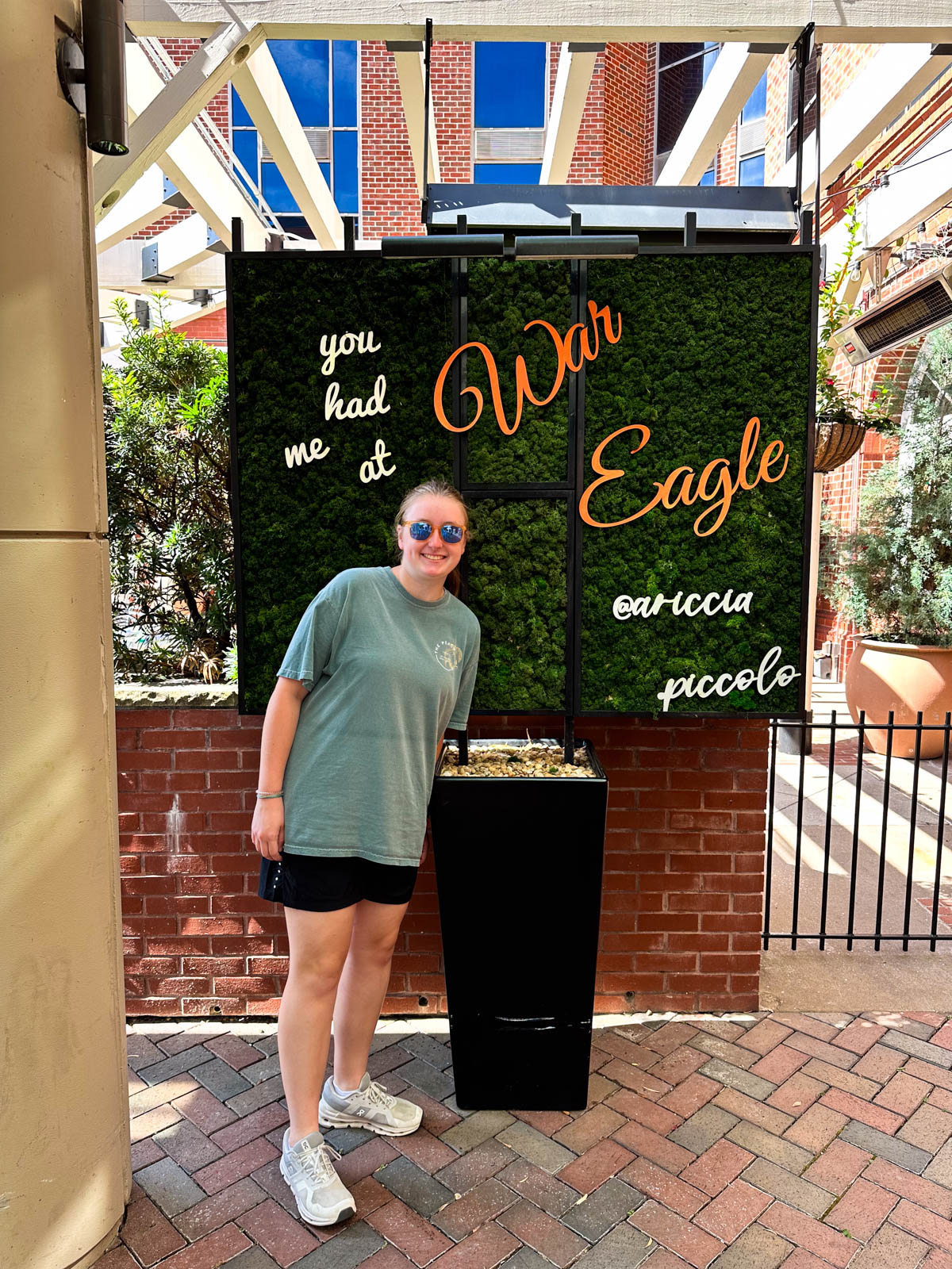 A girl stands in front of a War Eagle sign.