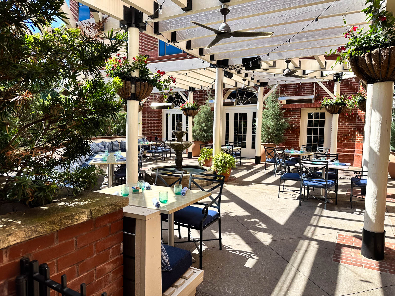 The outdoor dining area in front of the hotel features lots of shade and green plants.