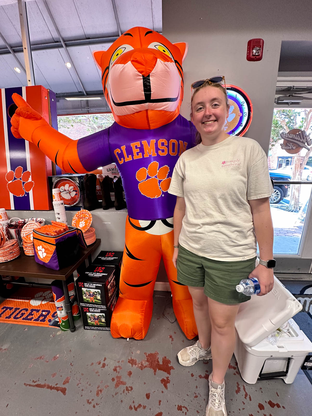 A girl stands next to a blow-up Tiger in a school spirit store.