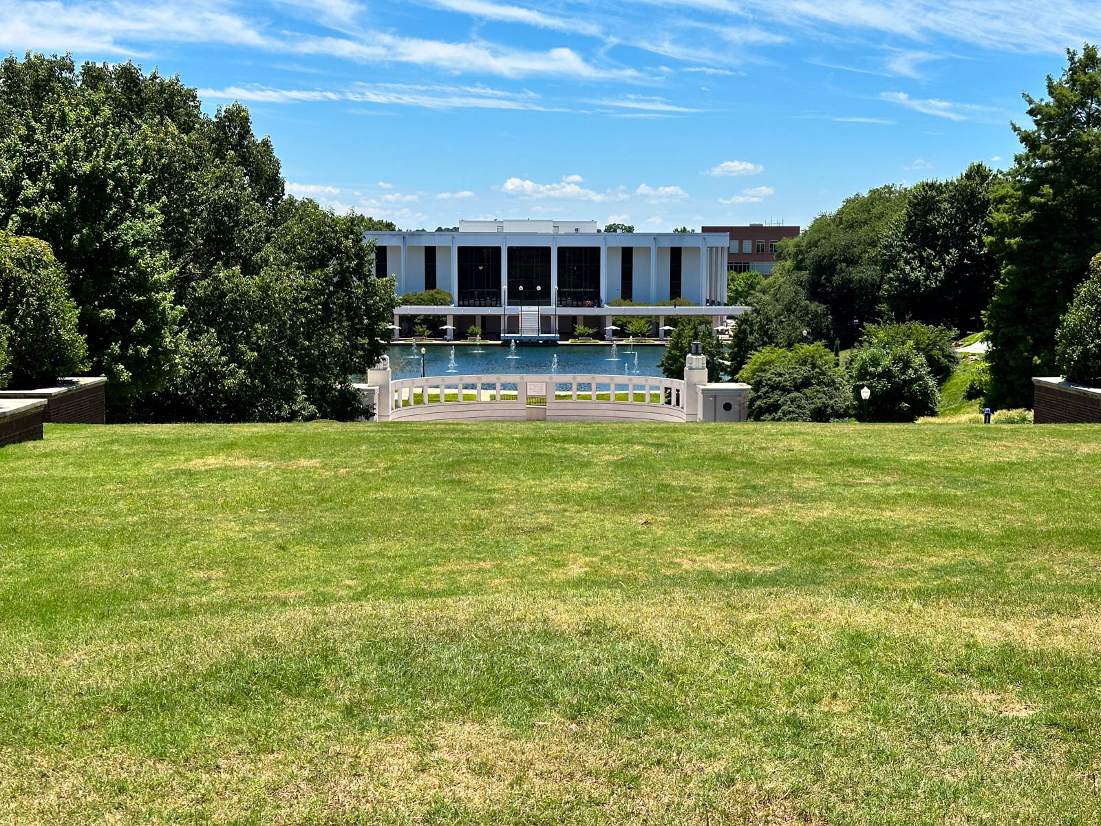 The library is seen at the bottom of a large green hill.