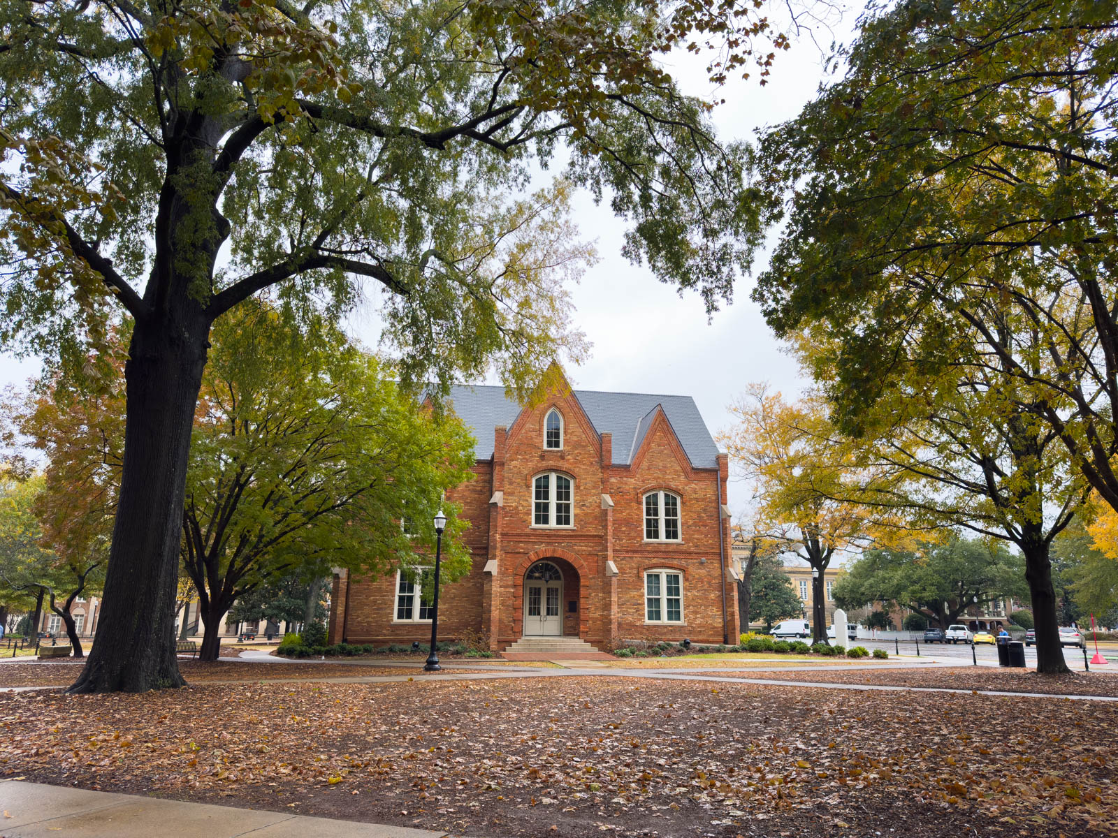 A red brick building on campus is surrounded by trees.