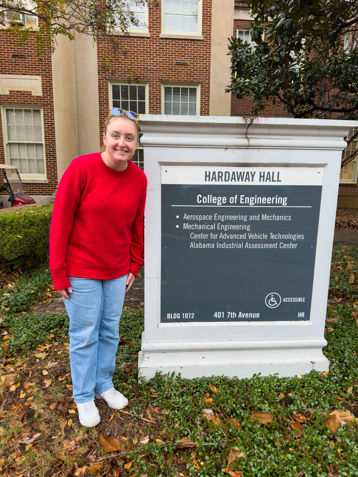 A girl stands outside the College of Engineering sign.