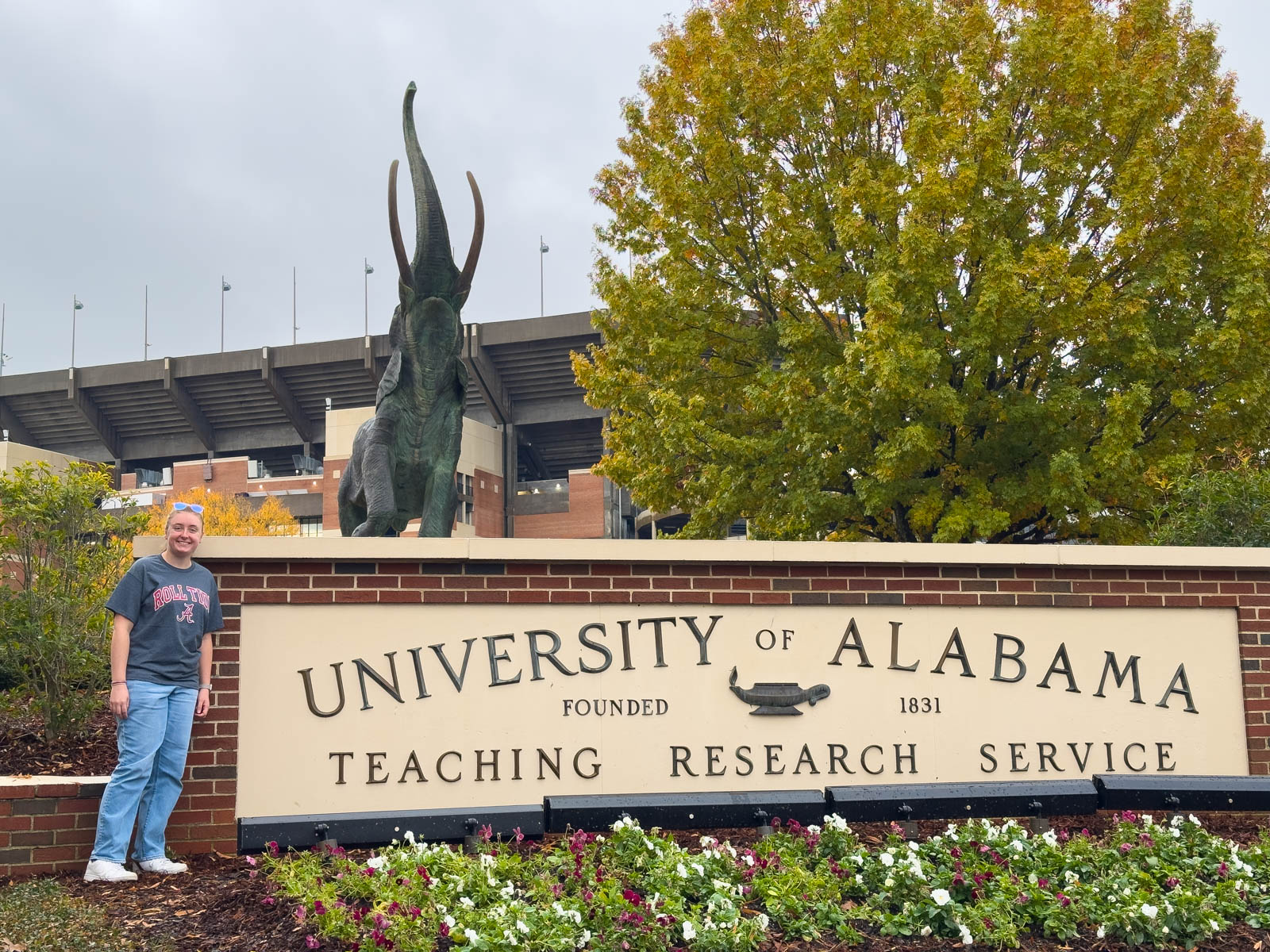 A girls stands by the University of Alabama sign.