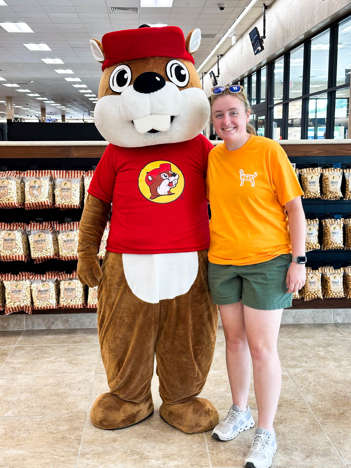 A girl  in an orange UT tshirt stands next to the Buccee's mascot.