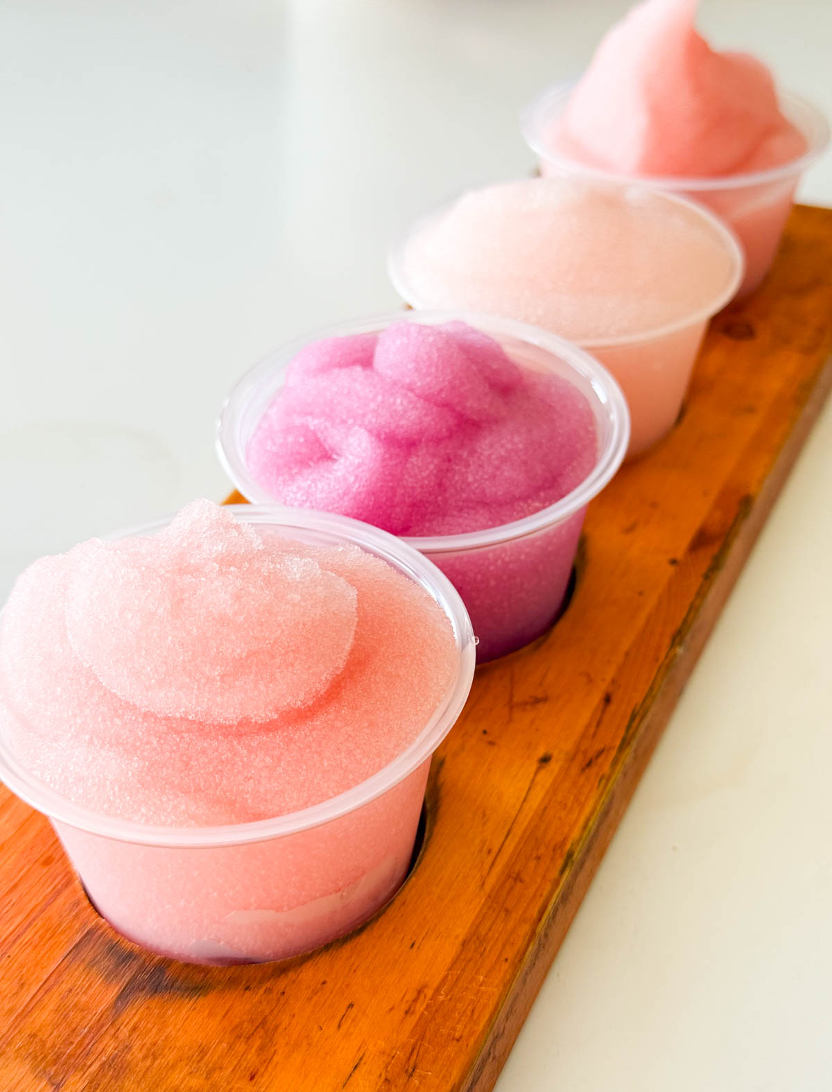 A row of four tasting cups of pink colored frose.