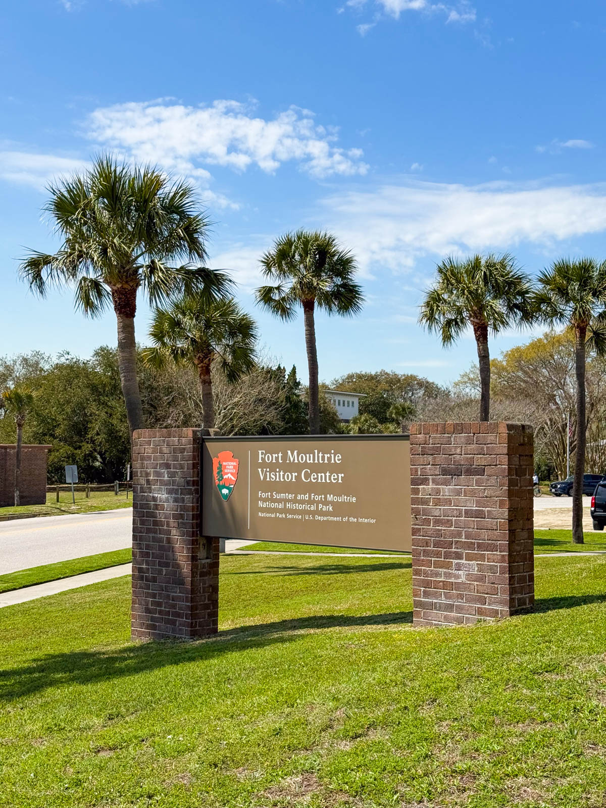 The sign for the visitor's center at Fort Moultrie has palm trees in the background.