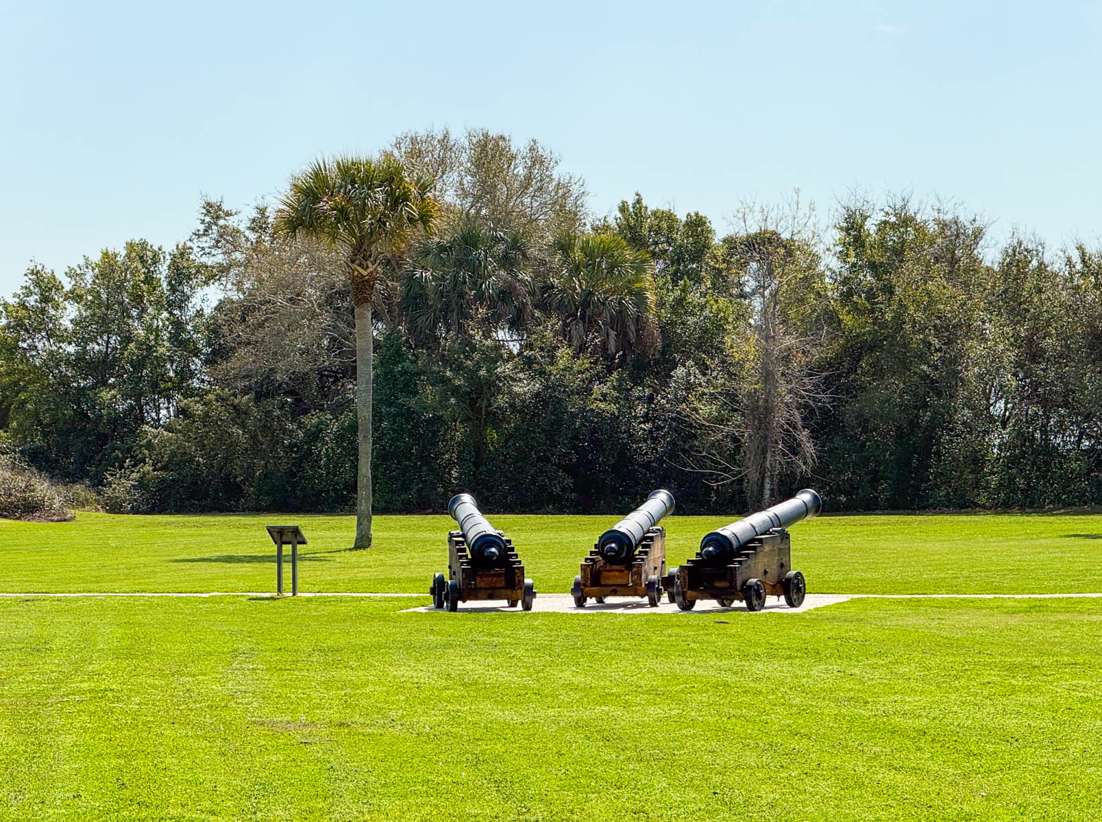 Three canons in an open green field.