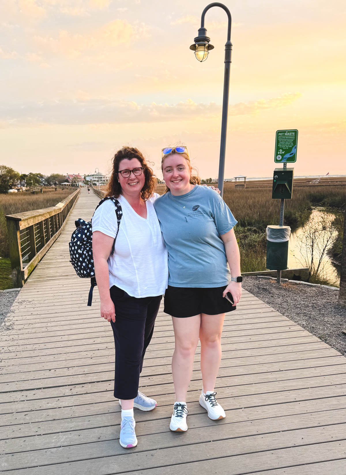 A mom and daughter pose for a picture on the Shem Creek boardwalk.