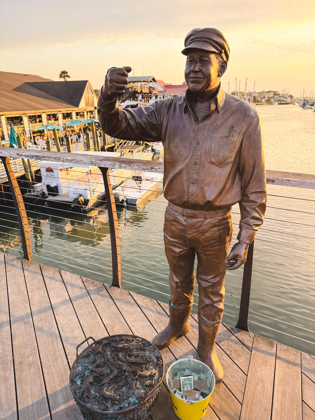 The statue and shrimp bucket on the bridge in Shem Creek that represents the Captain Wayne Magwood Fisherman's Memorial.