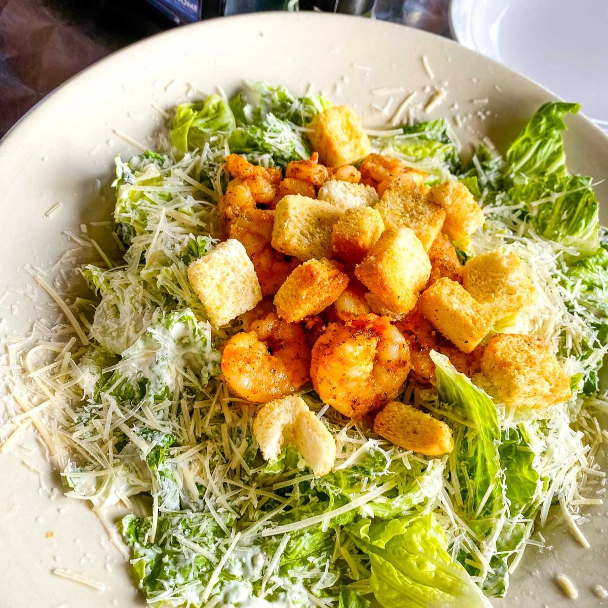 A fresh shrimp caesar salad on a plate.