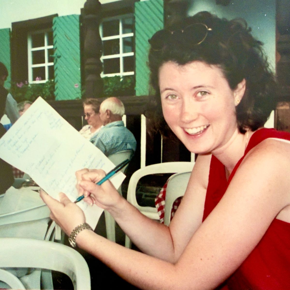 A vintage photo of a young woman holding a travel tag list and checking it off with a pen.